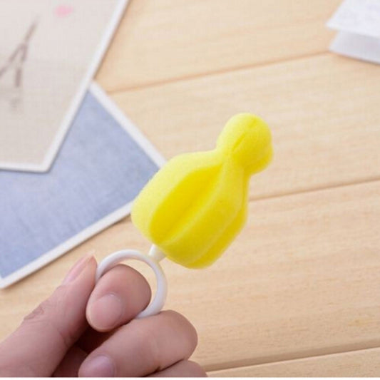 Yellow sponge brush with white ring handle held in a hand for pacifier or bottle cleaning