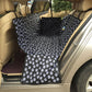Black pet seat cover hammock with white paw print, folded for rear seat fit