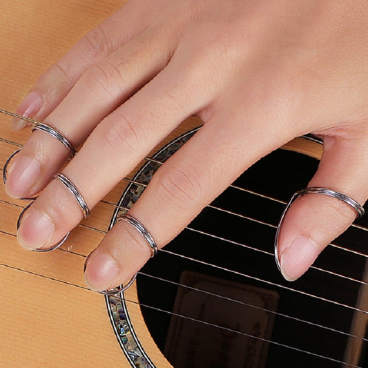 Metal spring ring guitar pick worn on fingers over guitar strings