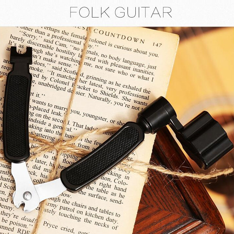 Guitar string changing tool set with black puller cone and clamp resting near guitar book
