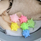 Set of 5 starfish-textured laundry cleaning balls on folded light fabric, pink green yellow blue