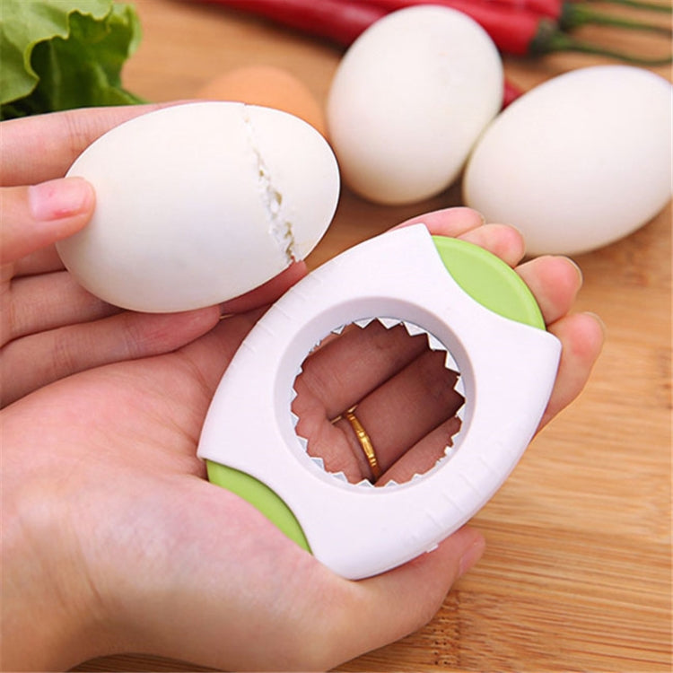 White egg opener held near cracked eggshell with serrated cutting edge