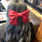 Red satin bow hairpin worn on long dark hair, large centered bow