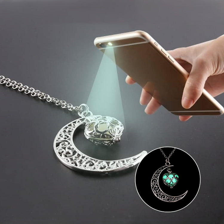 Silver crescent moon charm necklace with green glowing pendant, close-up glow view