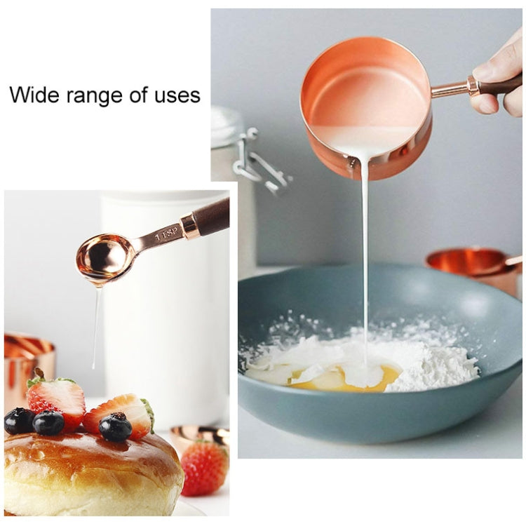 Copper measuring spoon with walnut handle pouring ingredients into a mixing bowl