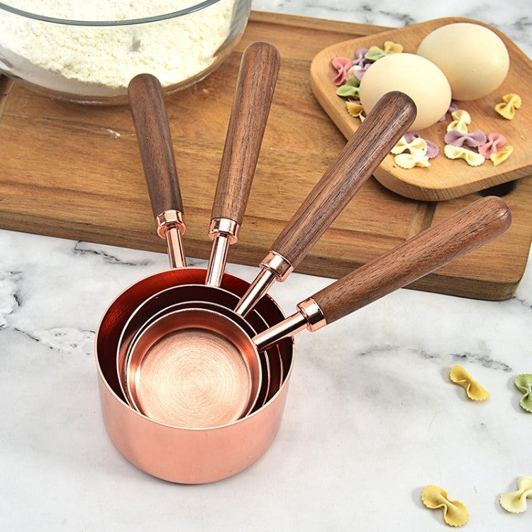 Copper measuring cups with walnut handles, four-piece set arranged on a wooden board