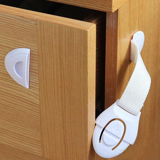 White invisible cabinet lock with fabric strap, attached to a wooden cabinet door