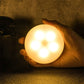 Round LED night light with warm amber glow, held in a hand