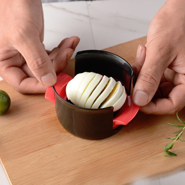 Egg slicer tool with black insert and red base, slicing a hard-boiled egg