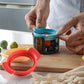 Egg slicer cup with teal lid and black container, with red accessory piece