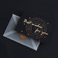 Bronzed “Best wishes for you” greeting card on black with circular gold design and envelope