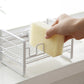 White metal dish drain rack with hands placing a beige sponge into the holder