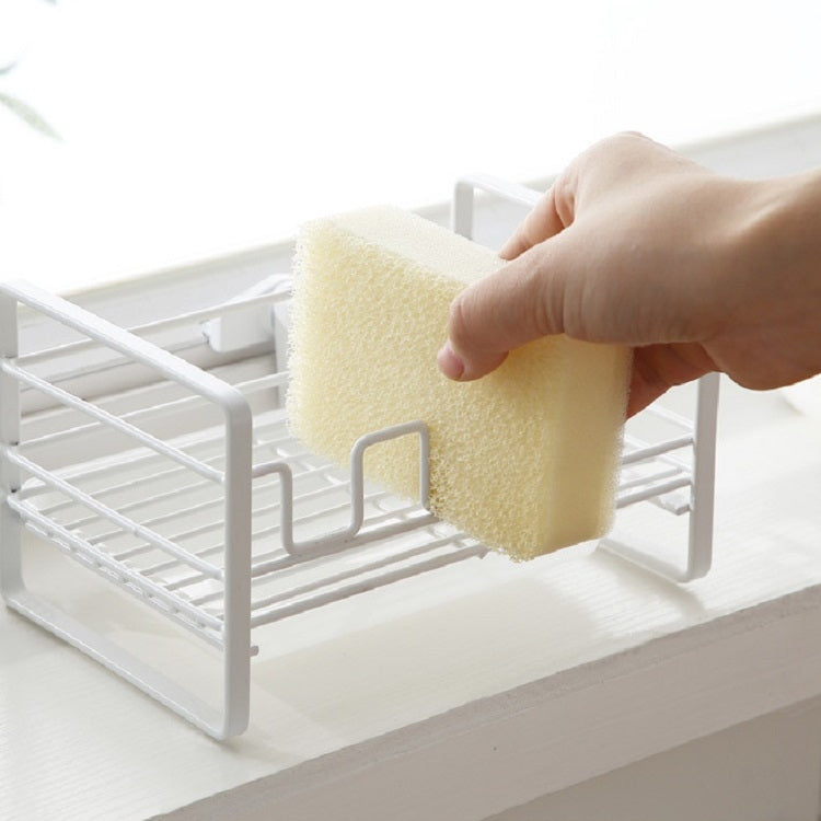 White metal dish drain rack with hands placing a beige sponge into the holder