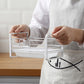 White metal dish drain rack on counter, hands holding a sponge/scrubber tray section