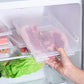 Clear plastic fresh-keeping box in refrigerator, hand placing lid with food inside