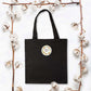 Black tote bag with small round thank you sticker in floral wreath style
