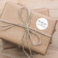 Round thank-you order sticker tied onto a kraft gift package with string