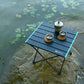 Folding camping picnic table set outdoors with black slatted top and blue side rails