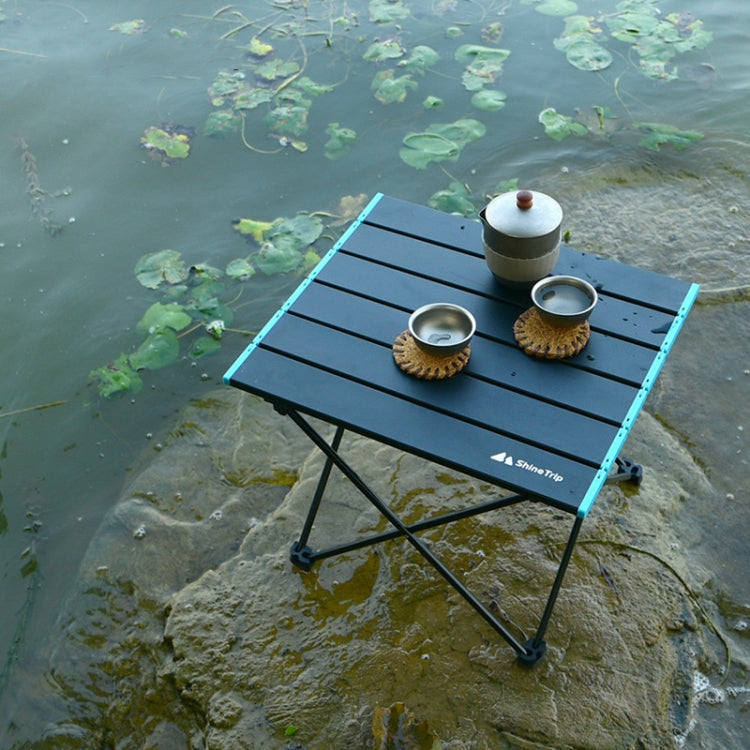 Folding camping picnic table set outdoors with black slatted top and blue side rails