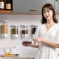 Wall-mounted grain storage tanks on kitchen wall with person holding a filled grain container