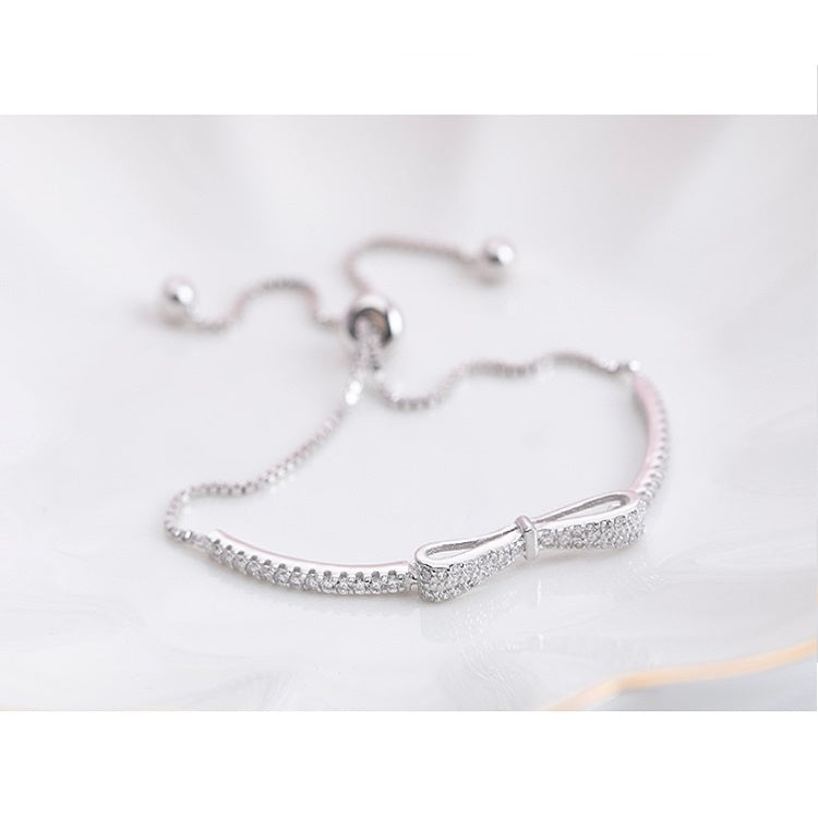 Silver bow stretch bracelet with heart-shaped sparkle charm and bead clasp