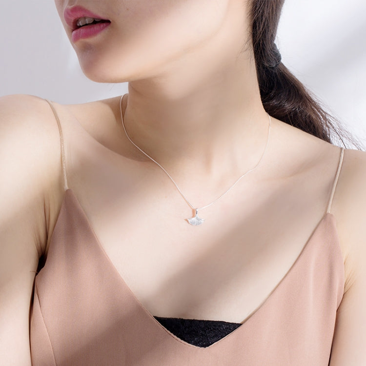 Sterling silver ginkgo leaf pendant necklace resting at collarbone