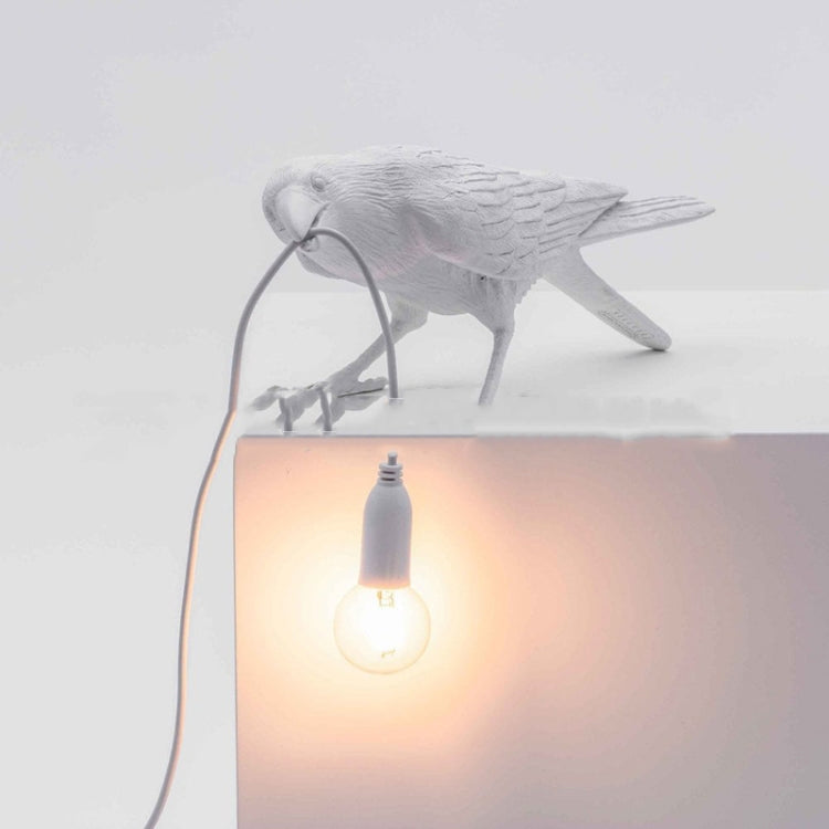 White bird figurine lamp perched on top with warm glowing bulb and hanging cord