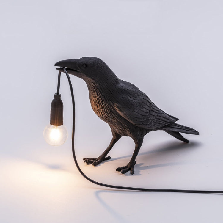 Black bird table lamp with lit E14 bulb and curved cable