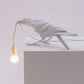 White bird table lamp perched on shelf with glowing E14 bulb and wire