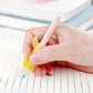 Yellow dolphin-shaped writing pen with wooden tip in hand over notebook lines