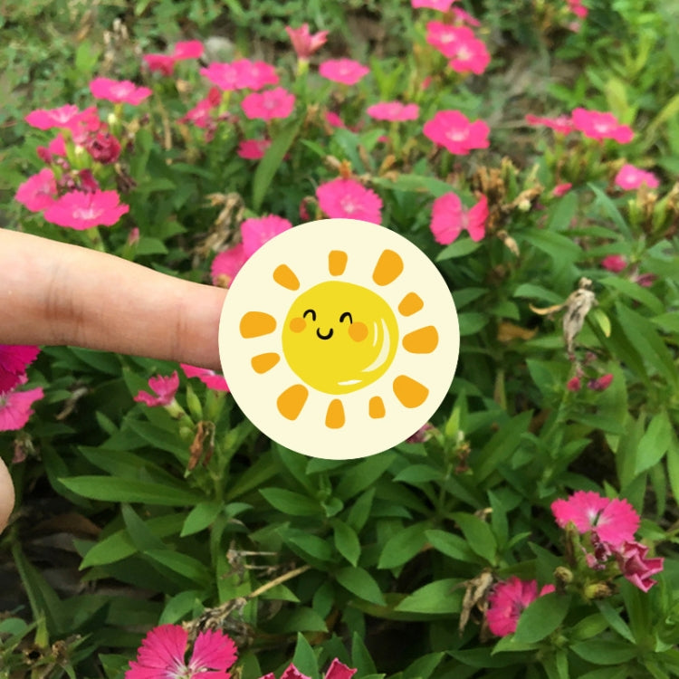 Single round thank-you sticker with smiling sun icon, held in front of pink flowers