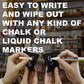 Hands writing on a small black tabletop chalkboard with a marker, ready to wipe