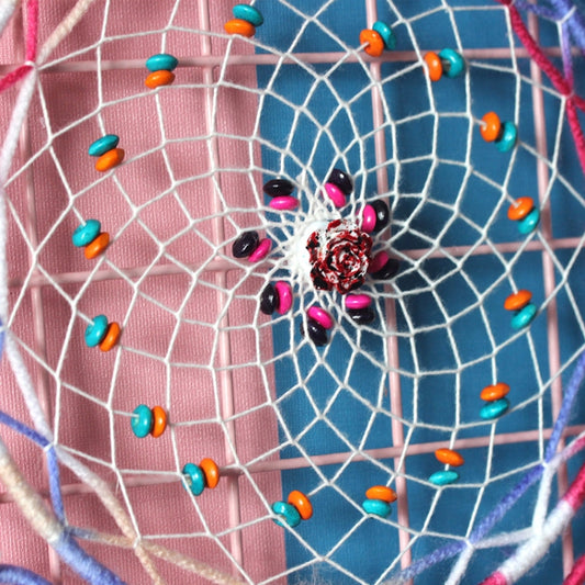 Woven dream catcher hoop close-up with bright beads and a flower-shaped center