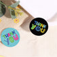 Circular Thank You stickers on fabric, including black and blue “Thank You” designs