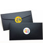 Black envelopes with small circular Thank You stickers featuring colorful text