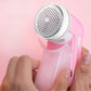 Pink USB lint and hair remover with round perforated shaving head held in hand