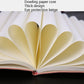 Open A5 notebook showing thick paper pages fanned out from the binding