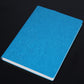 Blue PU notebook with embossed floral design on textured cover, white page edges