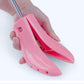 Pink boot expander clamp with adjustable prongs, held in a hand