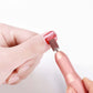 Rose gold electric nail polisher polishing a red nail with sanding sleeve