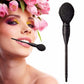 Blush makeup brush held near face, with black ribbed handle and oval bristle head