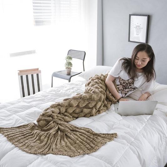Brown knit mermaid tail blanket with scalloped fish-scale texture, laid on a bed