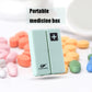 Light green folding pill box with plus symbol, shown with assorted tablets