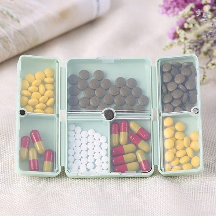Folding portable pill box opened, 6 compartments with assorted colored tablets