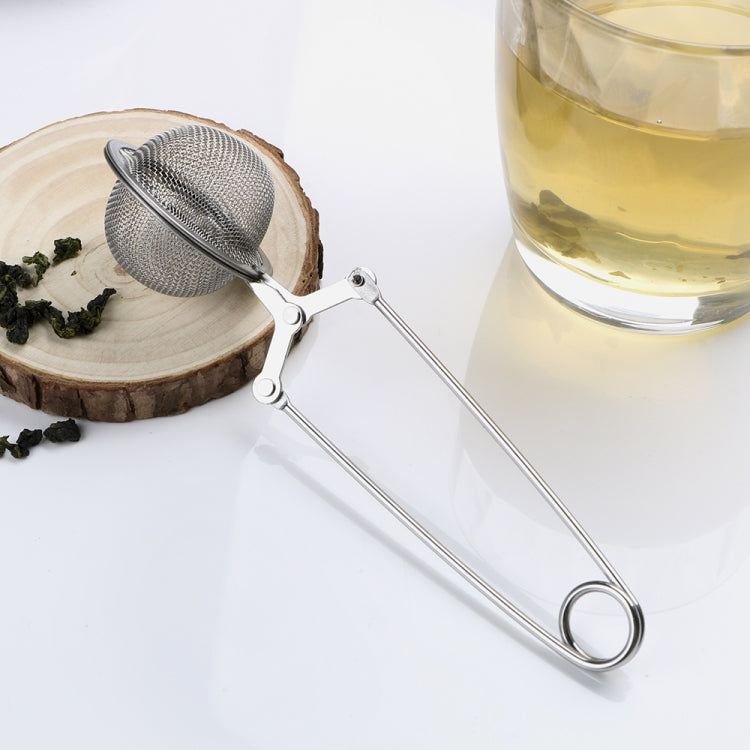 Stainless steel sphere mesh tea infuser with long handle next to a glass cup