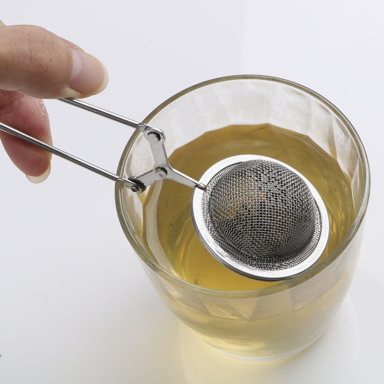 Stainless steel mesh sphere infuser placed in a clear cup, long tongs handle