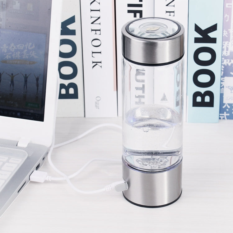 Portable water cup with clear chamber and stainless steel base; charging cable connected