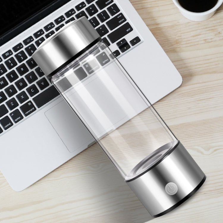 Portable stainless steel water cup tilted on desk, clear chamber and base button visible
