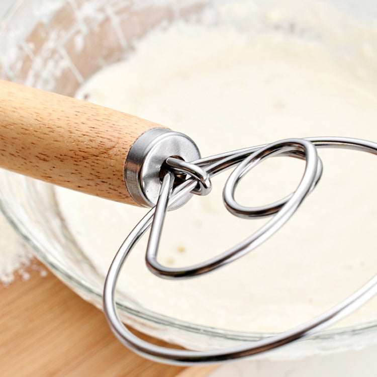 Oak-handled coil whisk stirring pale dough in a glass bowl