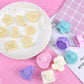 Embossed fondant cookies on a plate with blue and purple push molds nearby